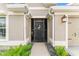 Home front door with storm door, front porch light, and manicured landscaping at 3750 Raspberry Ct, The Villages, FL 32163