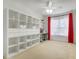 A functional bedroom with a ceiling fan, shelving, and window with red curtains at 4814 Luge Ln, Orlando, FL 32839