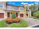 Inviting townhome exterior showcasing lush landscaping, garages, and a welcoming facade with multiple windows at 4814 Luge Ln, Orlando, FL 32839