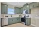 The kitchen features sage green cabinetry, stainless steel appliances, and a white tile backsplash at 5177 Blanket Flower St, Apopka, FL 32712