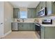 The kitchen features sage green cabinetry, stainless steel appliances, and a white tile backsplash at 5177 Blanket Flower St, Apopka, FL 32712