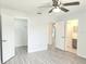 Bright bedroom featuring a ceiling fan, light gray floors, and white doors to the bathroom and closet at 651 Timbercrest Dr, Leesburg, FL 34748