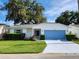Charming single-story home with a well-manicured lawn, blue garage door, and lush landscaping at 651 Timbercrest Dr, Leesburg, FL 34748