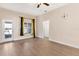 Sunny room with wood floors, neutral paint, ceiling fan, and ample natural light at 7732 Sloewood Dr, Leesburg, FL 34748