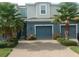 Charming townhome featuring a blue exterior, two-car garage, and lush palm trees at 1867 Holden Ridge Lane, Clermont, FL 34715