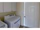 Well-lit laundry room with white washer, dryer, cabinets, and access to the exterior at 2947 Aldrich St, Eustis, FL 32726