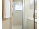 Bright shower features white tiles and fixtures, a window for natural light, and a glass shower door at 5317 Butterfly Ct, Leesburg, FL 34748