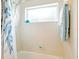 The shower-tub combo features white tiles, a window, and blue accents in the shower curtain and towels at 5317 Butterfly Ct, Leesburg, FL 34748