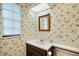 Bathroom with a single sink, wallpaper, framed mirror, and window at 9335 Silver Lake Dr, Leesburg, FL 34788