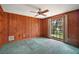 Wood paneled bedroom with ceiling fan, carpet, and a window overlooking the yard at 9335 Silver Lake Dr, Leesburg, FL 34788