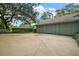 View of a spacious three-car garage with a large driveway and mature landscaping at 9335 Silver Lake Dr, Leesburg, FL 34788