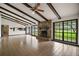 Bright living room featuring a stone fireplace, exposed beams, and large windows at 9335 Silver Lake Dr, Leesburg, FL 34788