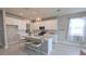 Bright kitchen features white cabinets, stainless steel appliances, center island, and modern pendant lighting at 2290 Raven Ridge Rd, Minneola, FL 34715