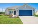 Charming home exterior featuring a blue garage door, matching front door and well manicured lawn at 9200 Se 48Th Court Rd, Ocala, FL 34480