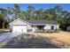 A charming single-story home featuring a gray exterior, new landscaping, a concrete driveway, and an attached garage at 1243 Ne 130Th Ter, Silver Springs, FL 34488