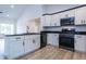 Bright kitchen featuring black appliances, black countertops, white cabinets, and new flooring at 1243 Ne 130Th Ter, Silver Springs, FL 34488