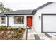 Modern white house with red door, gray and white paved walkway, and landscaping at 13050 Ne 7Th Loop, Silver Springs, FL 34488