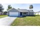 Charming single-story home featuring a two-car garage, blue front door, and a well-manicured lawn at 600 Ne 130Th Ter, Silver Springs, FL 34488