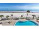 Overhead view from the balcony with palm trees, beach, ocean, pool, and lounge chairs at 89 S Atlantic Ave # 204, Ormond Beach, FL 32176