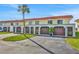 Townhouse exterior with multiple car garage, red roof, and green space with a healthy palm tree at 14 Ocean Palm Villa S # 14, Flagler Beach, FL 32136