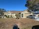 Tan one-story house with attached garage and driveway, surrounded by trees and landscaping at 1067 Dudley Dr, Kissimmee, FL 34758