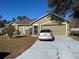 Tan one-story house with attached garage and driveway, surrounded by trees and landscaping at 1067 Dudley Dr, Kissimmee, FL 34758