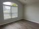 Bright bedroom featuring gray walls, wood-look flooring, and a large window offering plenty of natural light at 16862 Se 80 Bellavista Cir, The Villages, FL 32162