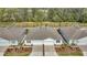 An aerial view of a white duplex with manicured landscaping, brick driveways, and a wooded backdrop at 5341 Nw 48Th Pl, Ocala, FL 34482