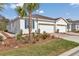 A street-level view of a white duplex with a two-car garage, manicured landscaping, and palm trees at 5341 Nw 48Th Pl, Ocala, FL 34482