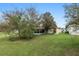 Backyard view of home with mature trees, green lawn, and a screened-in porch at 9481 Sw 93Rd Loop, Ocala, FL 34481