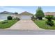 Wide driveway leading to a two-car garage, surrounded by lush greenery and mature trees at 9481 Sw 93Rd Loop, Ocala, FL 34481