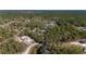 Distant aerial view of a house featuring a blue, screened in pool surrounded by lush greenery and forest at 12880 Sw 66Th St, Ocala, FL 34481