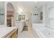 Bright bathroom with a jacuzzi tub, double vanity, and a view into the Primary bedroom at 906 Crestview Dr, Auburndale, FL 33823