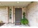 Inviting front entryway featuring a decorative door, brick accents, and lush potted plants at 906 Crestview Dr, Auburndale, FL 33823