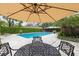 Outdoor pool area with stone tiling, privacy landscaping, umbrella, and outdoor seating at 906 Crestview Dr, Auburndale, FL 33823
