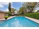 Beautiful in-ground pool area featuring brick trim, lush landscaping, and umbrella-covered seating at 906 Crestview Dr, Auburndale, FL 33823