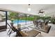 Beautiful sunroom with outdoor pool views, dining set, and cozy lounge chairs at 906 Crestview Dr, Auburndale, FL 33823