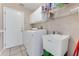 Laundry room with white washer and sink, cabinets, tile floor, and shelving at 915 Ashmeade Ct, Port Orange, FL 32127