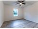 Well-lit bedroom with wood-look floors and a ceiling fan; ample natural light from the window at 24009 Sw Huckleberry Ln, Dunnellon, FL 34431