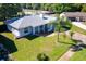 Aerial view of a single-story home featuring a lush green lawn, mature trees, and a spacious driveway at 8400 Mattituck Cir, Orlando, FL 32829