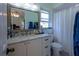 Bathroom with a vanity, decorative mirror, and window offering natural light at 8400 Mattituck Cir, Orlando, FL 32829