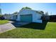 Single-story home featuring a green lawn, well-maintained landscaping, and a blue garage door at 8400 Mattituck Cir, Orlando, FL 32829