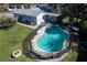 Aerial view of a backyard pool with safety fence, fire pit, and outdoor lounge area, ideal for relaxation and entertaining at 8400 Mattituck Cir, Orlando, FL 32829