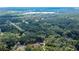 Expansive aerial view showcases the property surrounded by lush green forest with lake in background at 18 Malauka Loop Pass, Ocklawaha, FL 32179