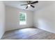 Bright bedroom with light gray floors, large window overlooking the greenery, and a ceiling fan at 18 Malauka Loop Pass, Ocklawaha, FL 32179
