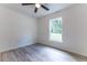 A bright bedroom with light gray flooring, ceiling fan, and a window overlooking the backyard at 18 Malauka Loop Pass, Ocklawaha, FL 32179