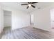 A bright bedroom with wood-look flooring, a ceiling fan, and two doorways to other rooms at 18 Malauka Loop Pass, Ocklawaha, FL 32179