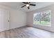 A bright bedroom features light gray flooring, a ceiling fan, and a window overlooking the lush backyard at 18 Malauka Loop Pass, Ocklawaha, FL 32179
