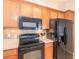 Cozy kitchen featuring wood cabinets, black appliances, and tile backsplash at 4410 Sw 52Nd Cir # 108, Ocala, FL 34474