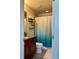 Well-lit bathroom with a granite vanity, dark wood cabinets, and a shower with a blue gradient curtain at 5108 Caspian St, St Cloud, FL 34771